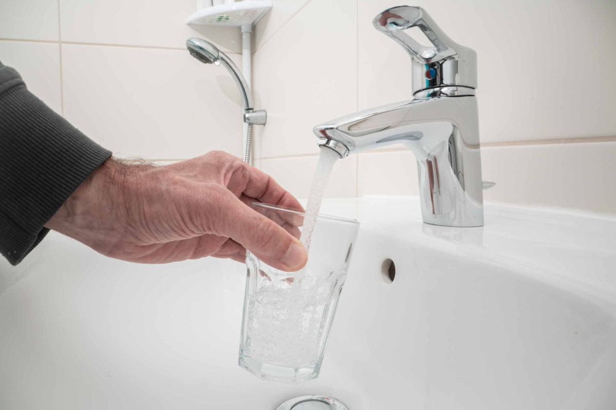 Osoba napełnia szklankę wodą z kranu