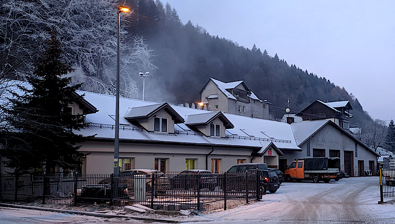Zimowa droga zasypana śniegiem, z widokiem na otaczające ją zaśnieżone drzewa