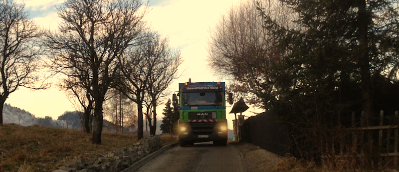 Ciężarówka jedzie drogą obok ogrodzenia
