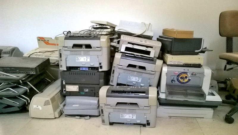 Stos drukarek i inne sprzęty biurowego leżą na podłodze